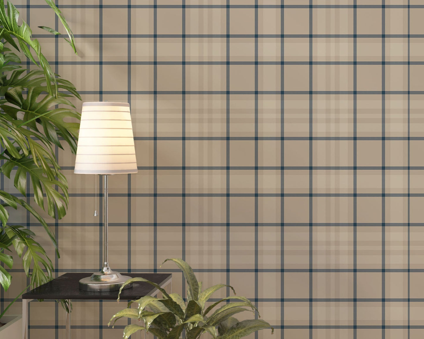 A modern living space featuring a warm soft caramel brown, beige, and cream plaid wallpaper accent wall. In the center, a light oak sideboard cabinet with wooden legs holds a small wooden tripod lamp, a geometric candle, and a round white ceramic vase with a single sprig of dried pampas grass. To the left, a woven basket sits on the light wood floor, filled with tall, fluffy pampas grass stalks and a draped blanket.
