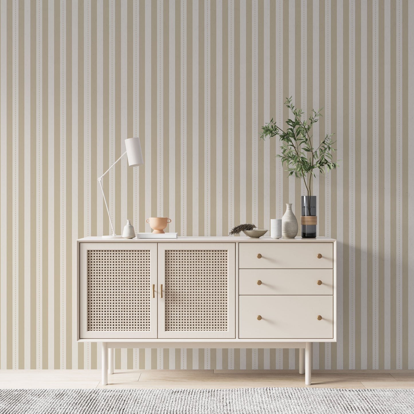 A minimalist hallway setup features a pale sand and cream striped wallpaper.
The detailed design shows clean vertical tan bands alongside cream stripes with thin dotted lines.
In front, a cream console cabinet with woven mesh doors stands against the wall.
The bright, neutral space is elegantly finished with a modern desk lamp and a leafy plant.
