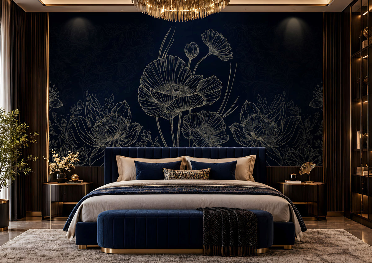A luxury bedroom featuring a dark navy blue floral wallpaper with white poppy line art, a matching navy velvet bed with beige and blue pillows, a navy velvet bench with gold trim, and a gold chandelier overhead.