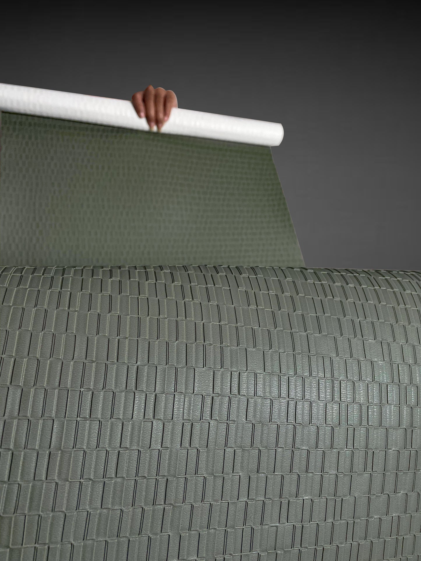 A high-resolution macro detail of Olive Green Deep Texture Wallcovering, showcasing a high-relief rectangular grid pattern. The image captures the precisely embossed, raised blocks and the subtle, fine-grained texture of the olive-green surface, highlighting its architectural depth and light-reflective qualities.