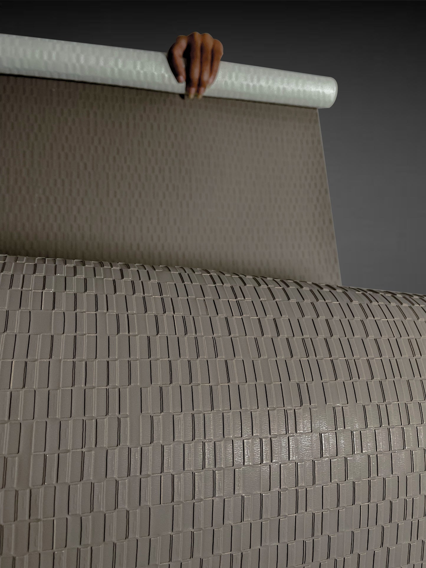 A high-resolution macro detail of Stone Grey Deep Texture Wallcovering, showcasing a high-relief rectangular grid pattern. The image captures the precisely embossed, raised blocks and the subtle, fine-grained texture of the taupe-grey surface, highlighting its architectural depth and light-reflective qualities.