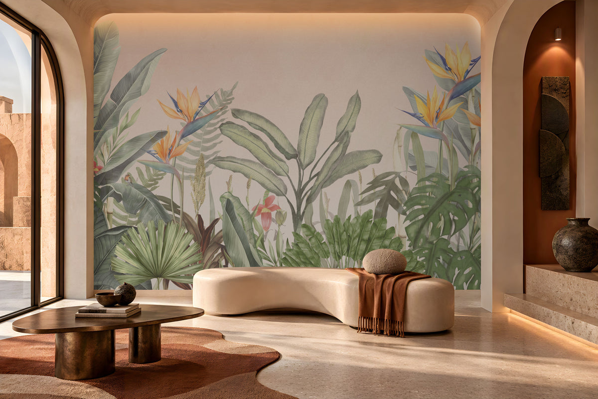Earthy Tropical Oasis - Warm Ivory Pink botanical wallpaper featuring lush tropical leaves, elegant bird-of-paradise flowers in soft yellow, orange, and muted blue, and layered olive green foliage against a warm ivory pink background. Displayed in a sophisticated contemporary lounge with a sculptural cream sofa, natural stone finishes, a dark wooden coffee table, and warm ambient lighting, this elegant tropical wallpaper adds a soft, earthy charm and a serene, nature-inspired atmosphere to modern