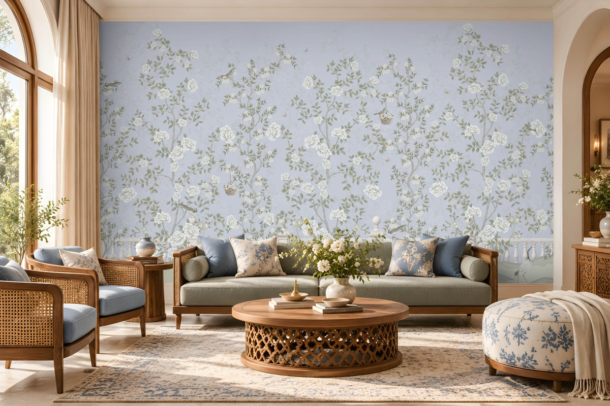 Elegant living room featuring Florentine Bloom misty blue floral wallpaper with white roses and botanical vines, complemented by a cream sofa, wooden furniture, and natural window lighting.