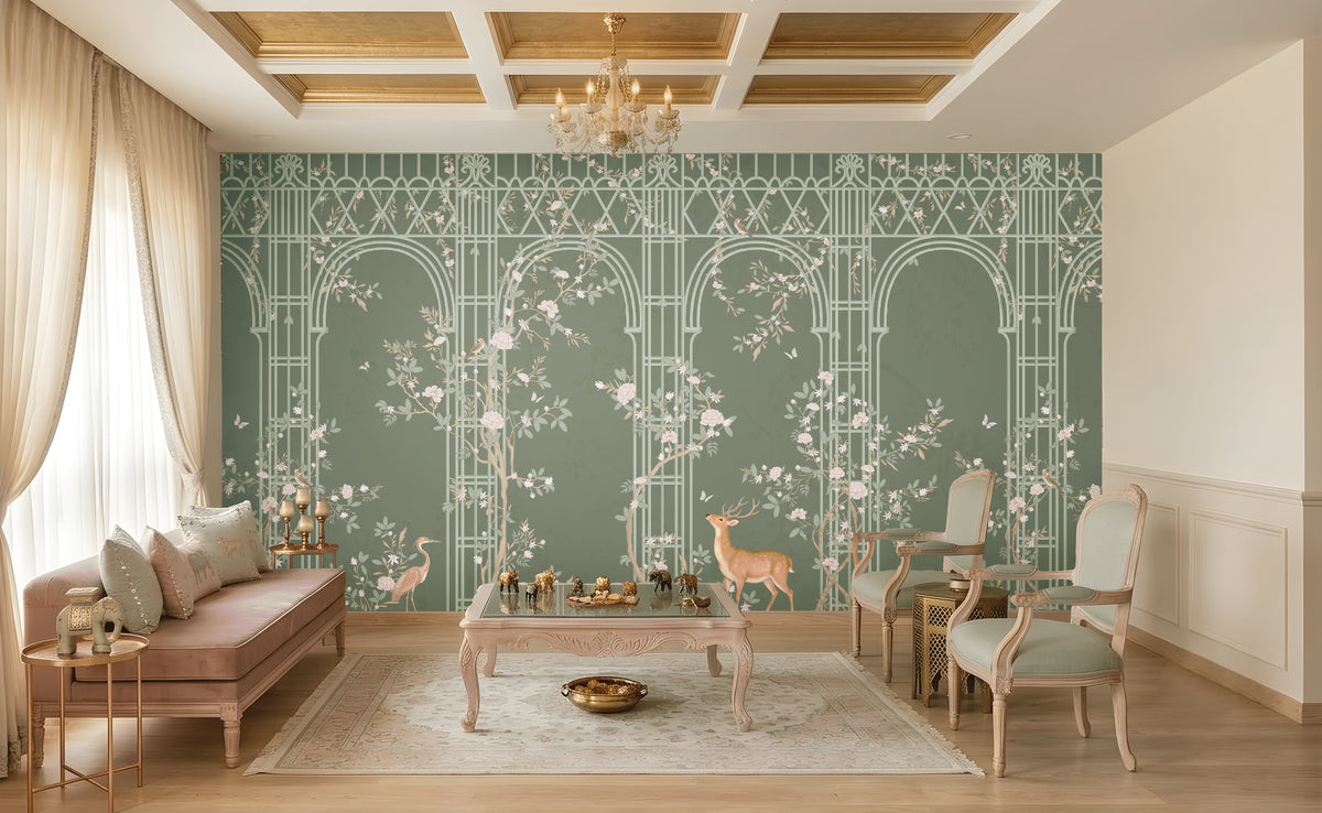 Morning Dew Trellis wallpaper in deep sage green featuring elegant arched trellis detailing, delicate flowering branches, perched birds, butterflies, and graceful woodland animals. Displayed in a luxurious living room with a coffered wood ceiling, crystal chandelier, blush-toned chaise lounge, vintage armchairs, and warm wood flooring, the mural creates a sophisticated garden-inspired focal point that blends classic elegance with nature-inspired charm.