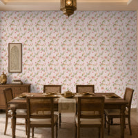 A dining room interior featuring a light pink floral wallpaper as the main wall backdrop, with a wooden dining table and woven-back chairs placed in front of it. A hanging lantern, sideboard, and decorative wall art are also visible.