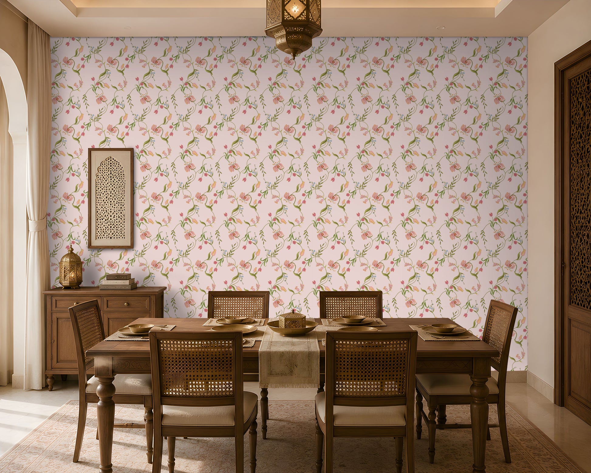 A dining room interior featuring a light pink floral wallpaper as the main wall backdrop, with a wooden dining table and woven-back chairs placed in front of it. A hanging lantern, sideboard, and decorative wall art are also visible.