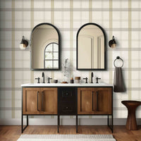 A neutral interior space features a classic plaid wallpaper in ivory and taupe tones.
The textured design displays a detailed grid pattern with intersecting beige, brown, and cream lines.
In front, a minimalist light-colored wooden wishbone chair with a woven seat is centered.
The simple setting is subtly completed by a small round side table holding a dark grey vase.