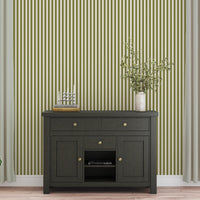 A bright dining area features a soft moss green and white striped wallpaper.
The clean design shows vertical green lines repeating across a textured white base.
In front, a warm wooden table is set with minimalist black chairs.
The sophisticated setup is completed by a contemporary black pendant light hanging above.