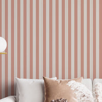 A bright and inviting living space features a warm peach and cream striped wallpaper.
The detailed design shows clean vertical peach bands alongside cream stripes with thin dotted lines.
In front, a plush white sofa is adorned with matching warm tan accent pillows.
The cozy room setup is beautifully completed with a light wood coffee table and a gold floor lamp.
