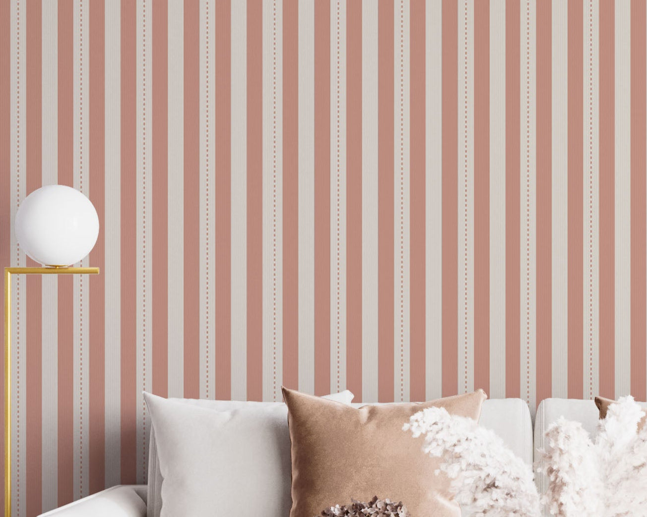 A bright and inviting living space features a warm peach and cream striped wallpaper.
The detailed design shows clean vertical peach bands alongside cream stripes with thin dotted lines.
In front, a plush white sofa is adorned with matching warm tan accent pillows.
The cozy room setup is beautifully completed with a light wood coffee table and a gold floor lamp.