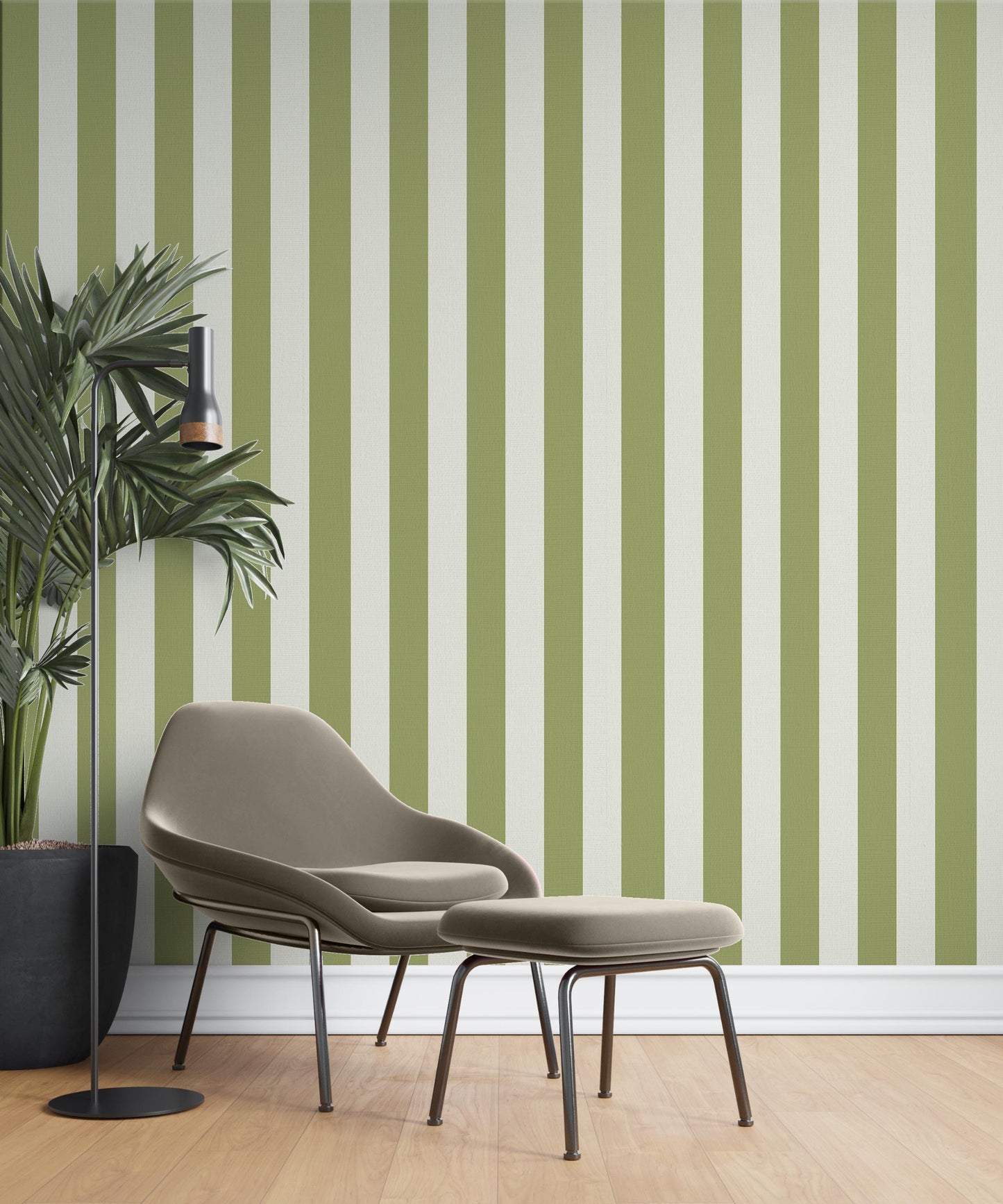 A cozy reading corner features a striped wallpaper pattern.
The wallpaper colors are an olive green and crisp white.
The design has clean, evenly spaced vertical stripes across the wall.
A modern taupe armchair sits in the center with a matching ottoman.
A tall black floor lamp stands next to a large potted plant.
The look is finished with light wood flooring and a white baseboard.