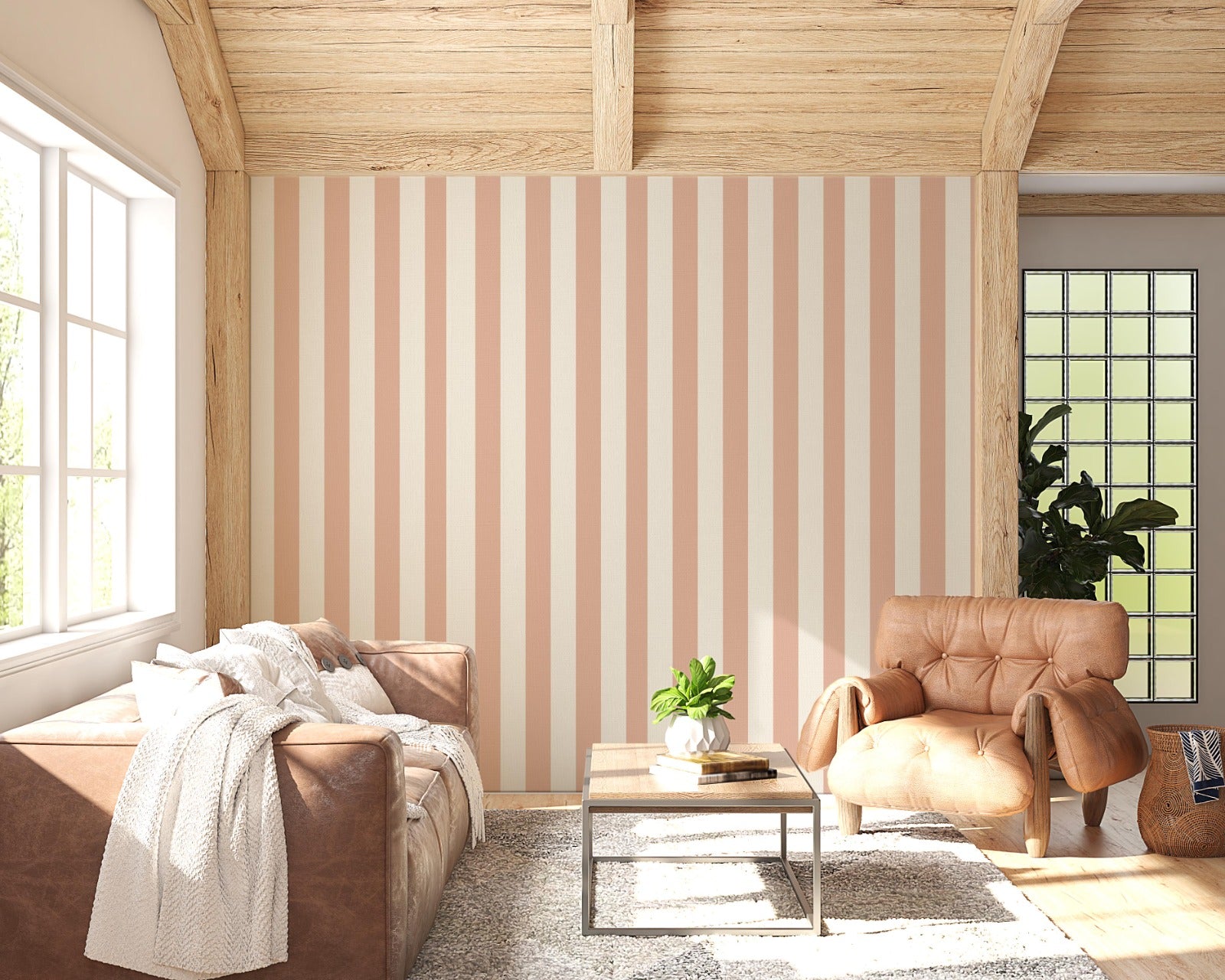 A sunlit living room features a warm honey-taupe and cream striped wallpaper.
The design showcases clean, evenly spaced vertical stripes across the central wall.
In front, a brown leather sofa and matching armchair frame a small coffee table.
The rustic space is complete with a textured area rug and a light wood beamed ceiling.