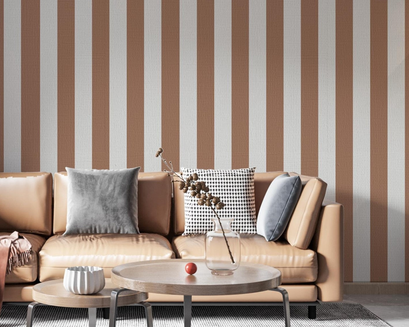 A modern living room features a warm cocoa brown and off-white striped wallpaper.
The design showcases clean, evenly spaced vertical stripes filling the central wall.
In front, a tan leather sofa with decorative pillows frames a round coffee table setup.
The stylish space is complete with a large area rug and an accent bar stool on the right.