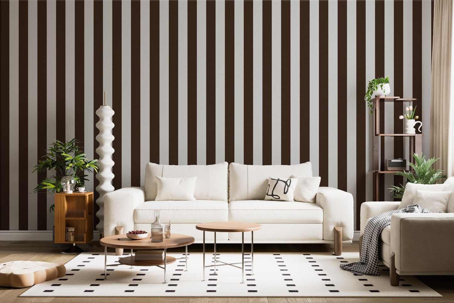 A stylish living room features a dark chocolate brown and crisp white striped wallpaper.
The design showcases clean, evenly spaced vertical stripes across the expansive back wall.
In front, a plush cream-colored sofa and matching armchair frame sleek round coffee tables.
The modern, high-contrast space is complete with a geometric area rug and potted green plants.