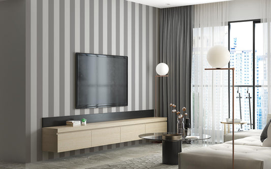 A stylish living room features a dark chocolate brown and crisp white striped wallpaper.
The design showcases clean, evenly spaced vertical stripes across the expansive back wall.
In front, a plush cream-colored sofa and matching armchair frame sleek round coffee tables.
The modern, high-contrast space is complete with a geometric area rug and potted green plants.