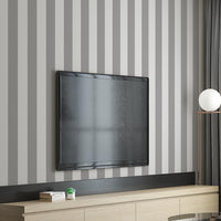 A stylish living room features a dark chocolate brown and crisp white striped wallpaper.
The design showcases clean, evenly spaced vertical stripes across the expansive back wall.
In front, a plush cream-colored sofa and matching armchair frame sleek round coffee tables.
The modern, high-contrast space is complete with a geometric area rug and potted green plants.