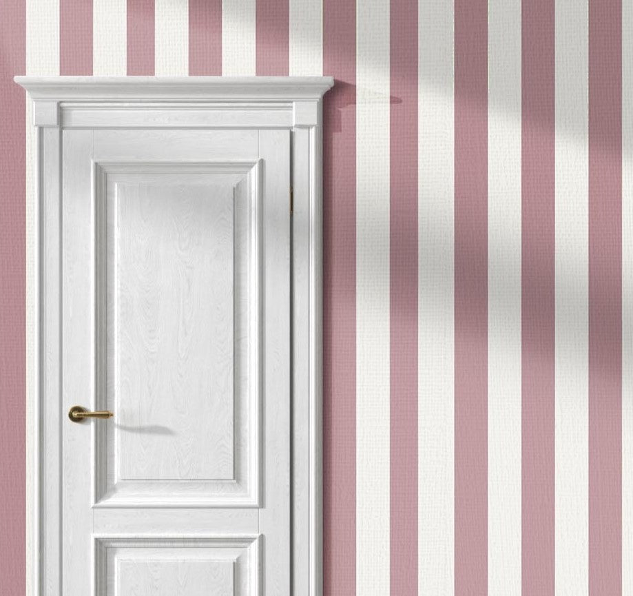 A stylish living room features a soft rosewood pink and white striped wallpaper.
The design showcases clean, evenly spaced vertical stripes across the expansive back wall.
In front, a plush cream-colored sofa and matching armchair frame sleek round coffee tables.
The modern, elegant space is complete with a geometric area rug and potted green plants.