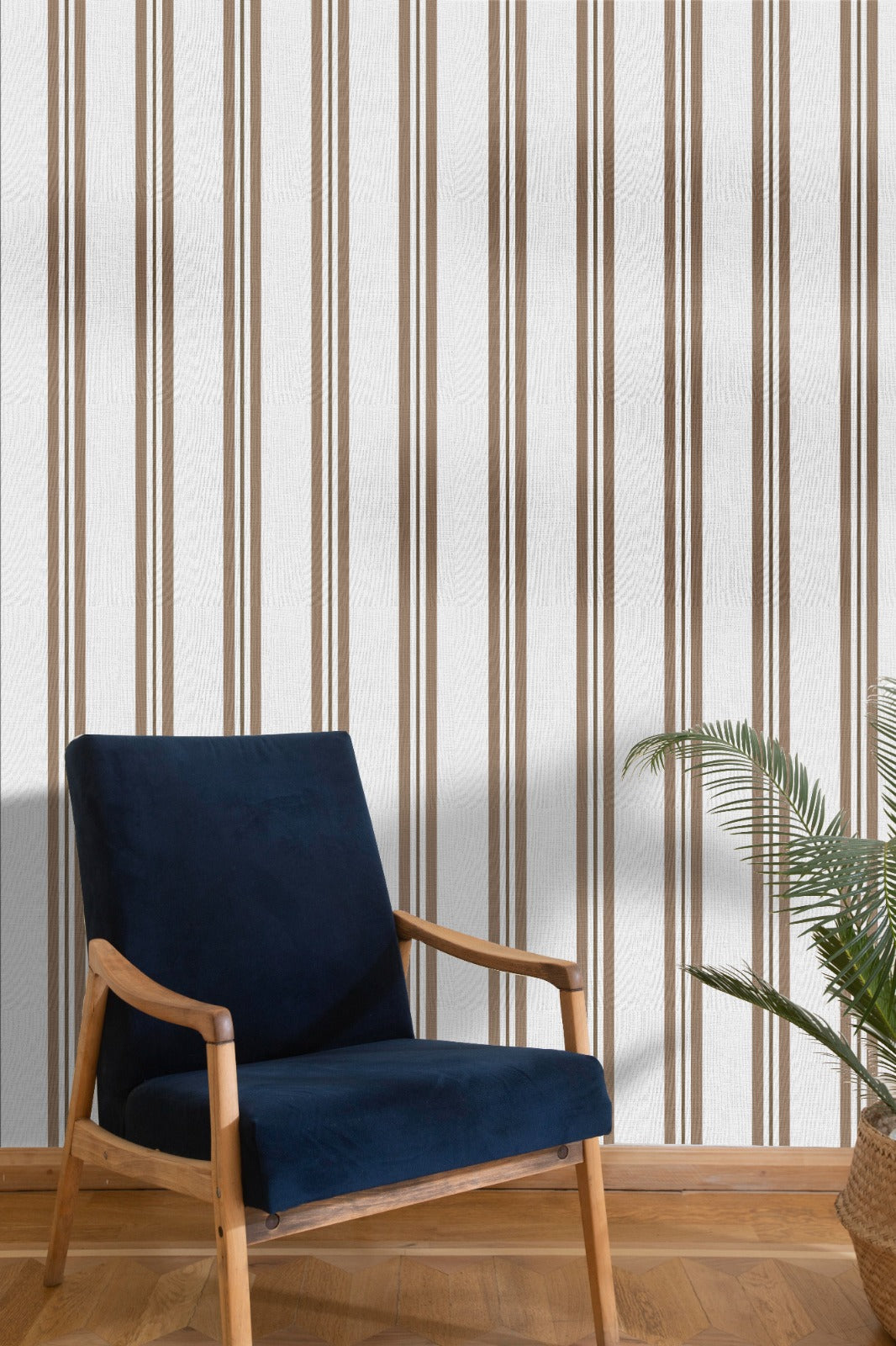 A bright seating area features a warm rustic mocha brown and white striped wallpaper.
The detailed design shows clean brown vertical lines repeating across a textured light base.
In front, a classic dark blue velvet armchair with a wooden frame sits comfortably.
The simple, inviting space is naturally accented with a leafy green potted plant nearby.