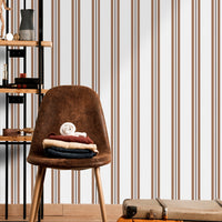 A warm dining area features a soft brown and white striped wallpaper.
The clean design shows vertical light brown lines repeating across a cream base.
In front, a sleek dark wooden table is paired with minimalist black chairs.
The sophisticated setup is completed by a contemporary black pendant light hanging above.