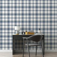 A clean workspace setup features a classic navy blue and white plaid wallpaper.
The detailed design shows intersecting dark blue stripes forming grids on a white base.
In front, a sleek dark grey desk holds a small lamp, notebooks, and office accessories.
A modern dark grey desk chair with a rounded back completes the organized study area.