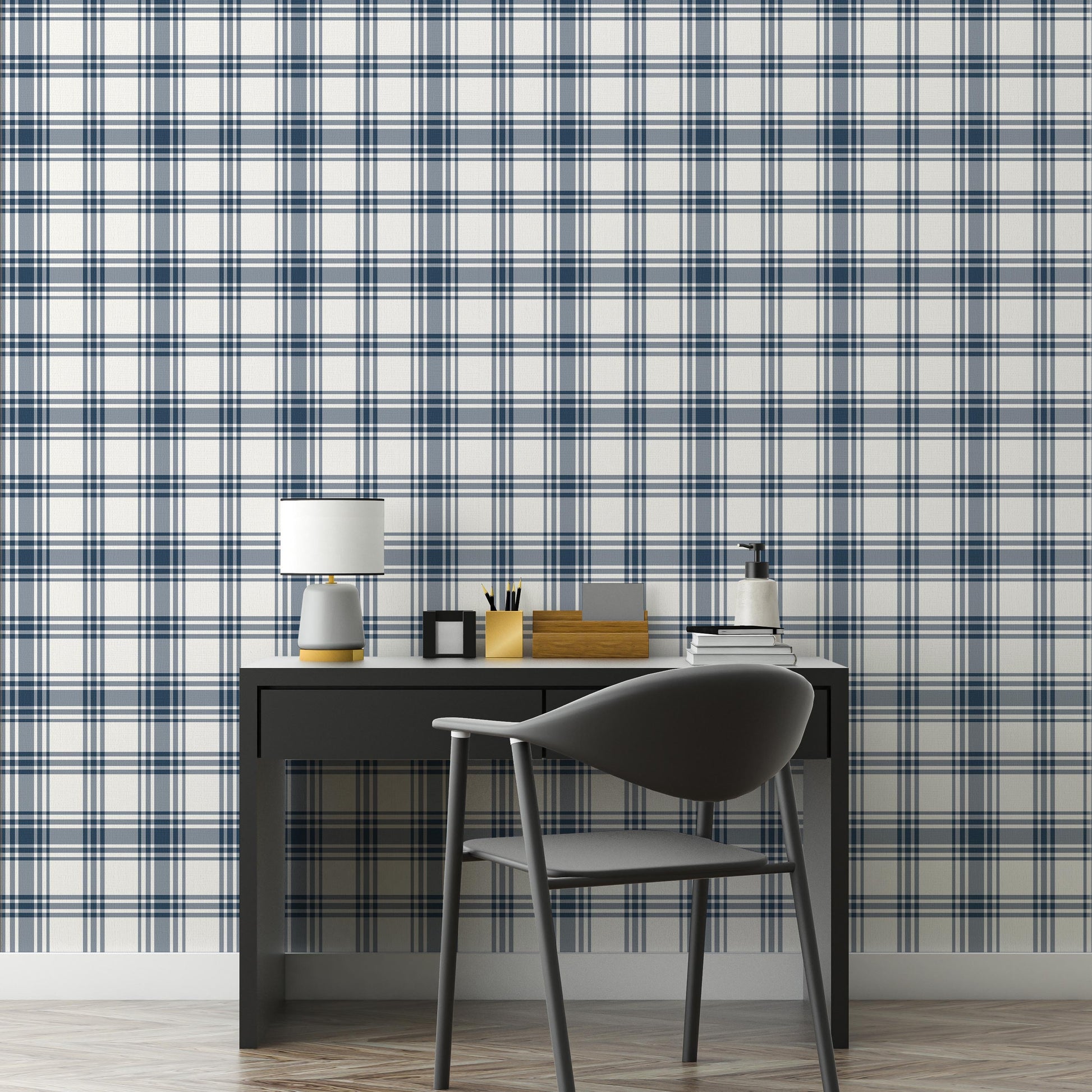 A clean workspace setup features a classic navy blue and white plaid wallpaper.
The detailed design shows intersecting dark blue stripes forming grids on a white base.
In front, a sleek dark grey desk holds a small lamp, notebooks, and office accessories.
A modern dark grey desk chair with a rounded back completes the organized study area.
