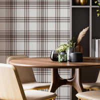 A cozy dining area features a classic warm brown and cream plaid wallpaper.
The detailed design shows intersecting brown stripes forming grids on a light base.
In front, a round wooden dining table is surrounded by four matching chairs.
A tall, dark grey open bookshelf stands on the right side to complete the space.