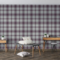 A cozy bedroom features a rich mulberry purple and beige plaid wallpaper.
The detailed pattern shows intersecting dark purple lines forming a clean grid on a light base.
In front, a neatly made bed with a dark purple comforter centers the stylish room.
A simple black wire-frame side table holding a single flower completes the minimalist setup.