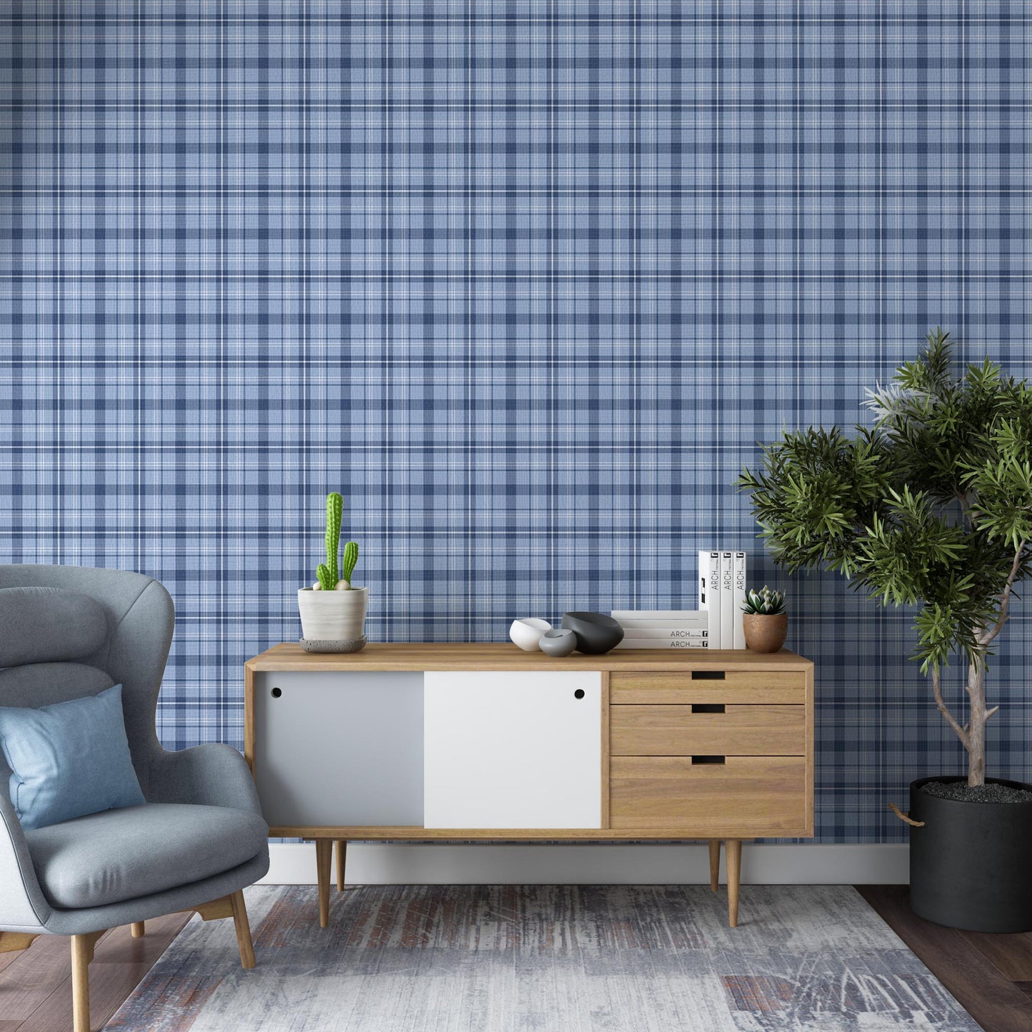 A contemporary living room with blue plaid wallpaper creating a textured backdrop. The space features a gray upholstered armchair, a mid-century modern wooden sideboard with decorative objects and books, and a large potted indoor tree on dark wood flooring.
