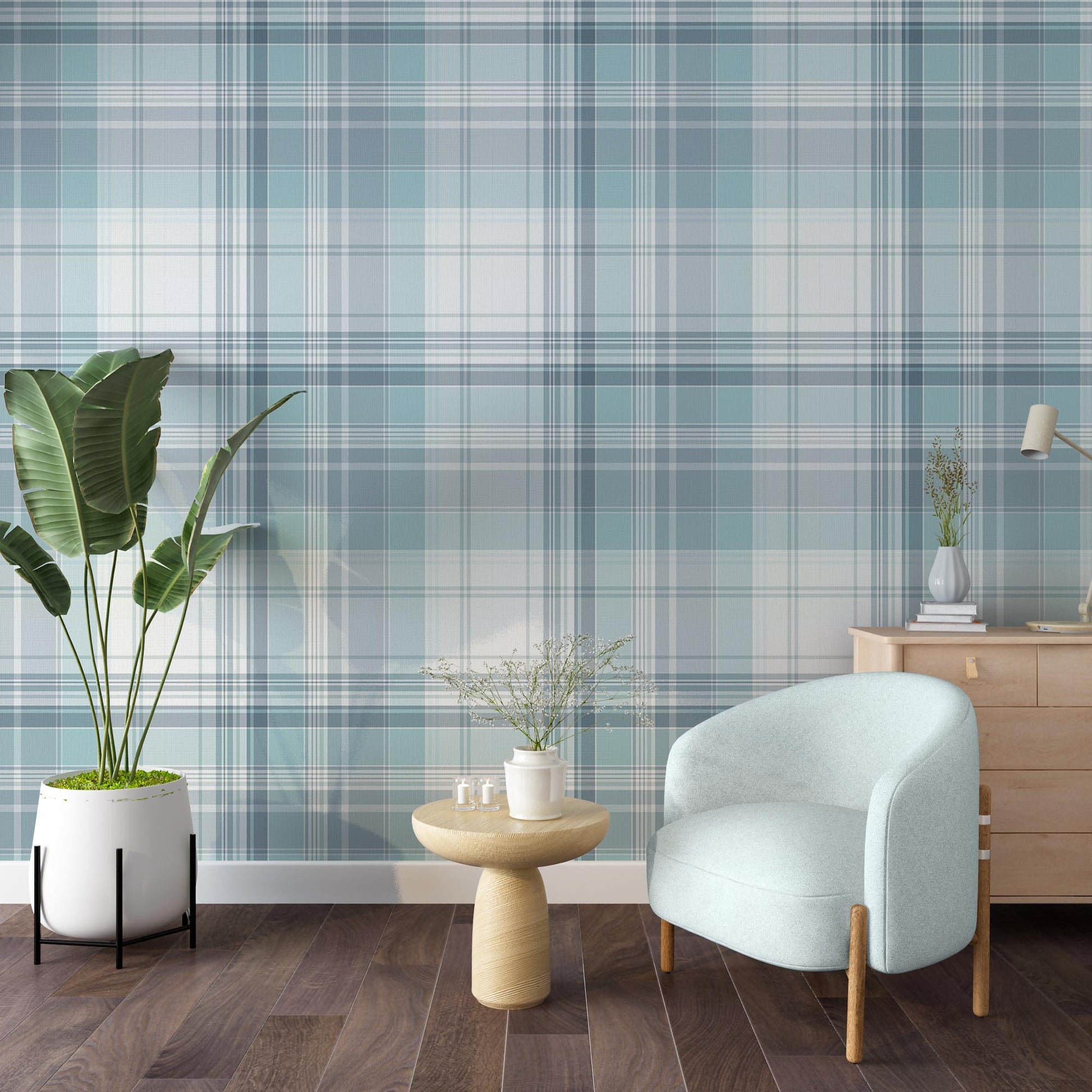 A bright room features a light blue and white plaid wallpaper pattern.
The wallpaper colors include shades of soft aqua, dusty blue, and white lines.
A rounded light blue armchair sits on the dark wood floor.
A small, round wooden side table holds a white vase with flowers.
A large green plant in a white pot stands on the left side.
A light wood dresser with a small desk lamp sits on the right.