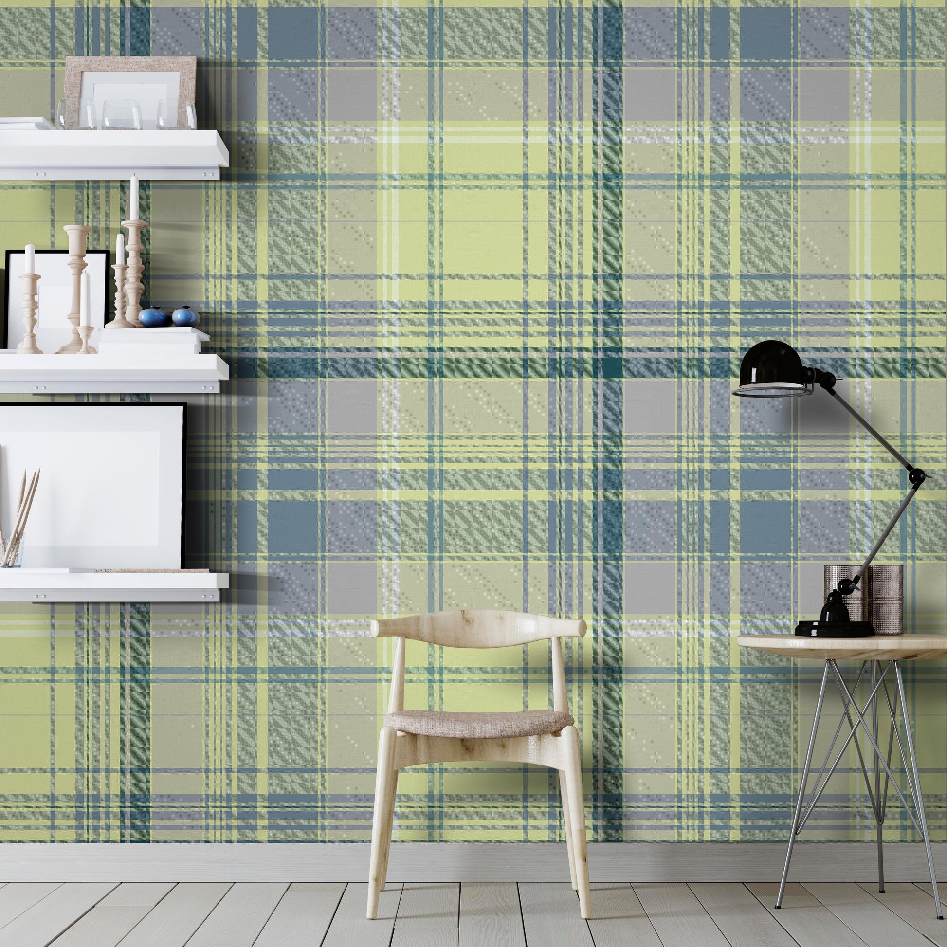 A modern interior featuring green and blue plaid wallpaper with a soft tartan pattern. The room includes floating white shelves with decorative objects, a light wood chair, and a small round table with a black adjustable desk lamp on a light wood floor.