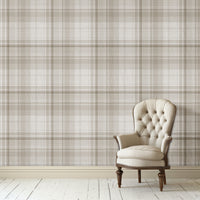 A classic interior scene featuring a beige tufted armchair with dark wooden legs placed against a neutral plaid wallpaper in soft taupe and cream tones. The room has white painted wood flooring and a calm, elegant aesthetic.