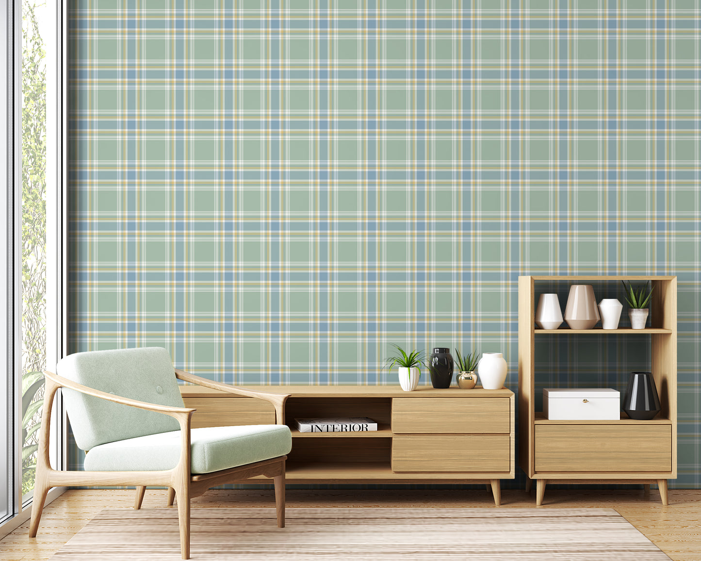 A light and airy living room featuring a misty sage green, soft blue, and pale yellow plaid wallpaper accent wall. In the foreground, a mid-century modern armchair with a pale mint-green cushion sits on a striped area rug. Behind the chair, a long light oak media console with open shelving displays books and potted succulents. To the right stands a matching small light oak bookshelf styled with white, beige, and black ceramic vases and a decorative white box.