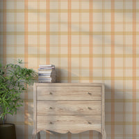 A warm interior space features a classic plaid wallpaper in soft tan and cream tones.
The textured design displays a detailed grid pattern with intersecting orange, yellow, and beige lines.
In front, a rustic wooden chest of drawers stands against the wall holding a stack of books.
The charming interior setting is completed by a leafy green potted plant placed on the left side.