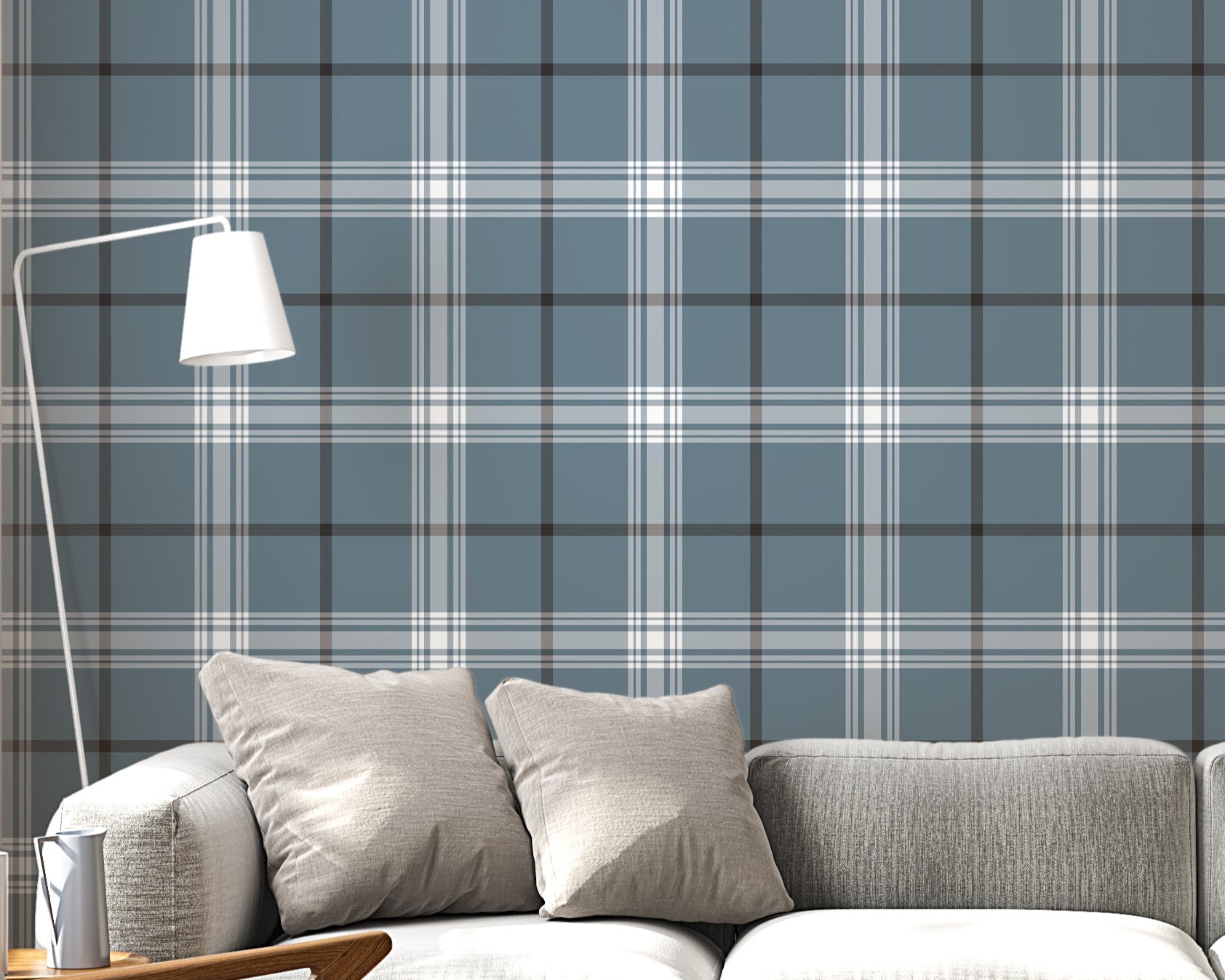 A modern living room features a serene blue-steel grey and white plaid wallpaper.
The detailed design shows intersecting white and dark lines creating grids on a blue base.
In front, a light grey fabric sofa with matching cushions sits centered in the room.
The bright space is complete with a wooden armchair, coffee tables, and a floor lamp.