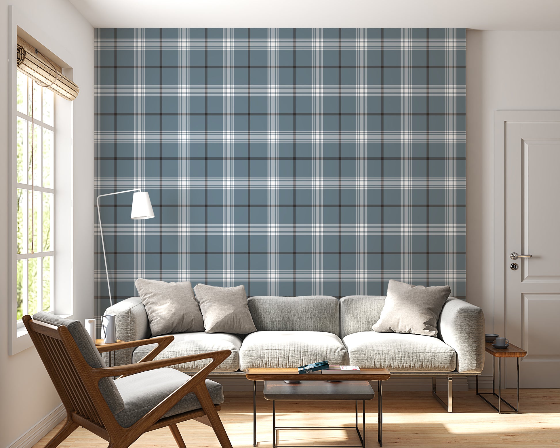 A modern living room features a serene blue-steel grey and white plaid wallpaper.
The detailed design shows intersecting white and dark lines creating grids on a blue base.
In front, a light grey fabric sofa with matching cushions sits centered in the room.
The bright space is complete with a wooden armchair, coffee tables, and a floor lamp.