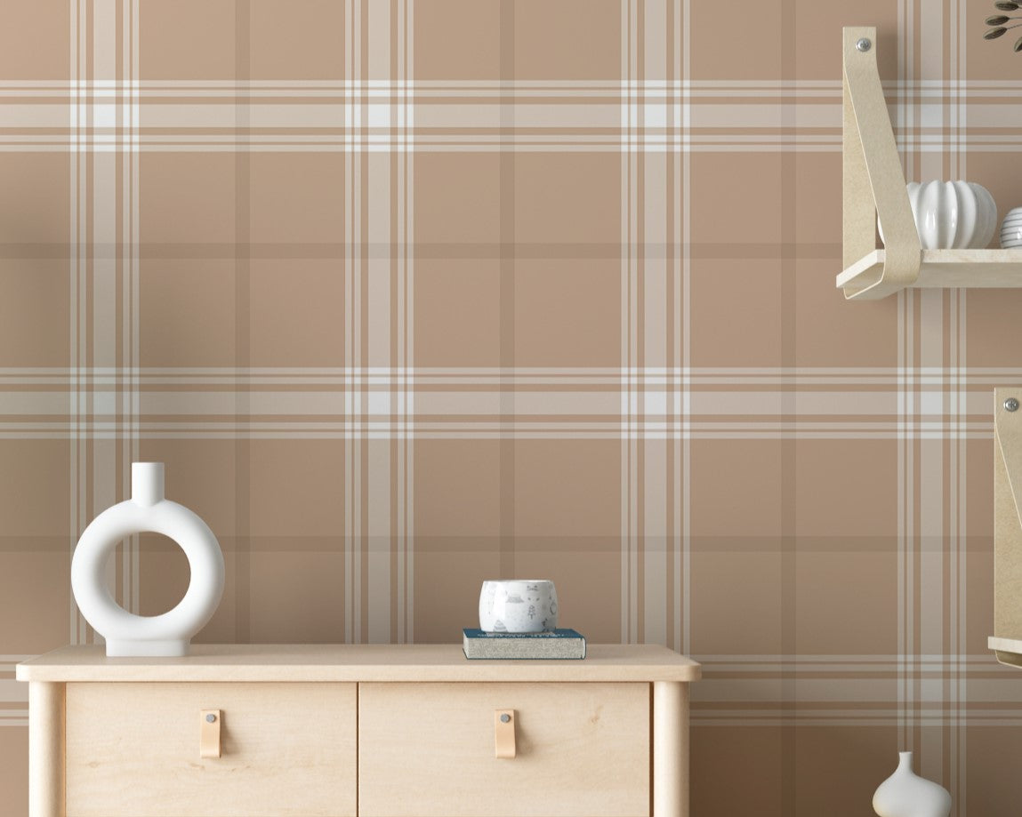 A stylish living area features a warm taupe brown and white plaid wallpaper.
The detailed design shows intersecting white and brown lines creating grids on a taupe base.
In front, a cream-colored wooden sideboard with woven rattan doors is centered nicely.
The serene setup is accented with a white desk lamp, pottery, and a leafy green plant.