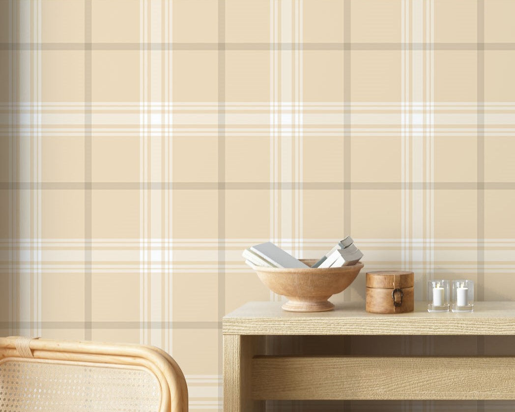 A stylish living area features a soft pale almond and off-white plaid wallpaper.
The detailed design shows intersecting light brown lines forming grids over a sandy base.
In front, a cream-colored wooden sideboard with woven rattan doors is centered nicely.
The serene setup is accented with a white desk lamp, pottery, and a leafy green plant.
