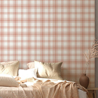 A cozy bedroom features a warm peach and cream plaid wallpaper.
The detailed design shows intersecting soft orange lines forming grids on a light base.
In front, a large bed with fluffy pillows and blankets is neatly arranged.
The bright, relaxing space is finished with natural wooden accents and a textured rug.