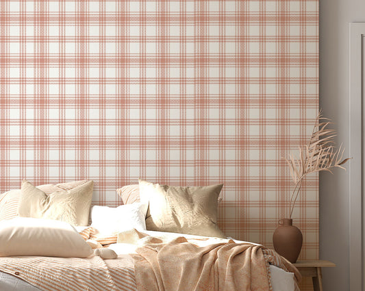 A cozy bedroom features a warm peach and cream plaid wallpaper.
The detailed design shows intersecting soft orange lines forming grids on a light base.
In front, a large bed with fluffy pillows and blankets is neatly arranged.
The bright, relaxing space is finished with natural wooden accents and a textured rug.