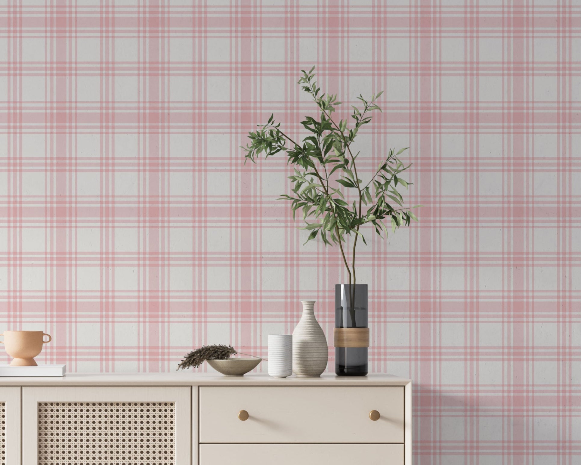 A charming living area features a soft baby pink and white plaid wallpaper.
The detailed design shows intersecting light pink lines forming grids over a light base.
In front, a cream-colored wooden sideboard with woven rattan doors is centered nicely.
The serene setup is accented with a white desk lamp, pottery, and a leafy green plant.