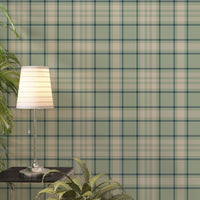 A light and airy living room featuring a vintage moss green, soft brown, and cream plaid wallpaper accent wall. In the foreground, a mid-century modern armchair with a pale mint-green cushion sits on a striped area rug. Behind the chair, a long light oak media console with open shelving displays books and potted succulents. To the right stands a matching small light oak bookshelf styled with white, beige, and black ceramic vases and a decorative white box.