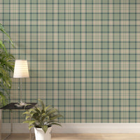 A light and airy living room featuring a vintage moss green, soft brown, and cream plaid wallpaper accent wall. In the foreground, a mid-century modern armchair with a pale mint-green cushion sits on a striped area rug. Behind the chair, a long light oak media console with open shelving displays books and potted succulents. To the right stands a matching small light oak bookshelf styled with white, beige, and black ceramic vases and a decorative white box.