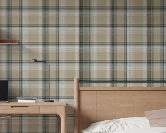 A closeup of a modern bedroom and study area featuring a prominent stone-beige plaid wallpaper. On the left, a light oak wooden desk holds a closed laptop, a small stack of books, and a sleek, matte black metal desk lamp. To the right, a matching light oak wooden headboard and bedframe are visible, with a crisp white duvet pillow and a soft beige accent pillow resting on top.