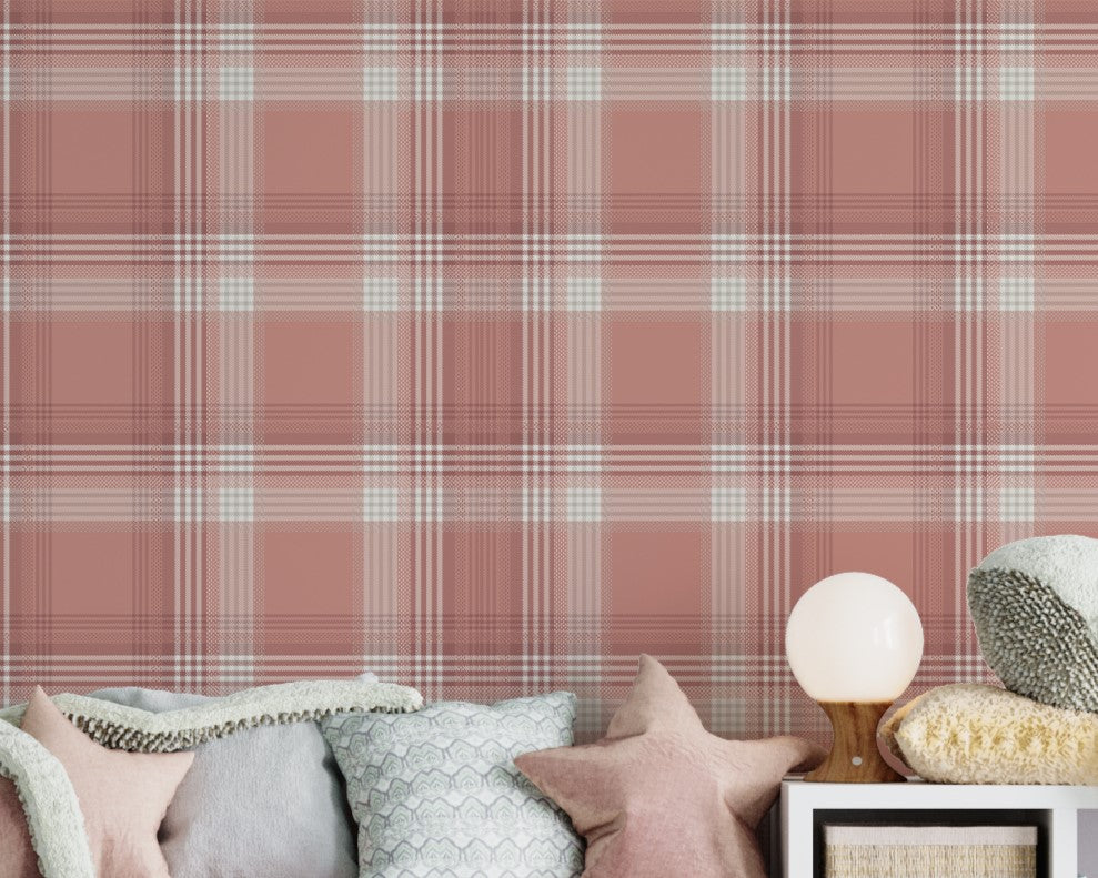 A children's playroom or nursery featuring a dusty terracotta pink and white plaid wallpaper accent wall. A long white storage unit sits against the wall, incorporating cubbies filled with books, storage baskets, and a central built-in bench with a pink velvet cushion and star-shaped pillows. Large plush sea creature toys, including a white octopus, a grey whale, and a blue whale, are scattered across the storage unit and on a yellow textured rug below. The room is finished with light grey wood plank floori