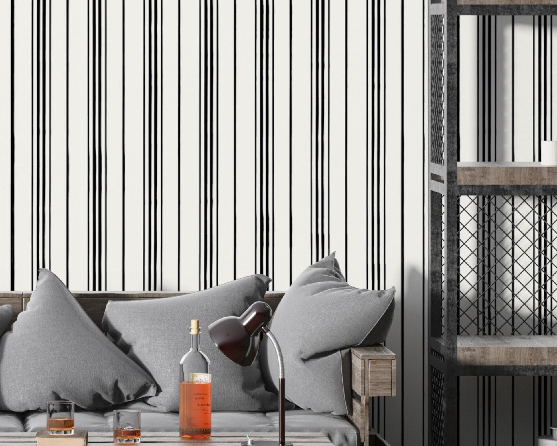 A modern interior scene with a gray cushioned sofa set against a white wall patterned with thin vertical black stripes. A wooden side table and black desk lamp sit beside bottles and glasses on a coffee table, while an industrial-style shelving unit with metal mesh panels stands on the right.