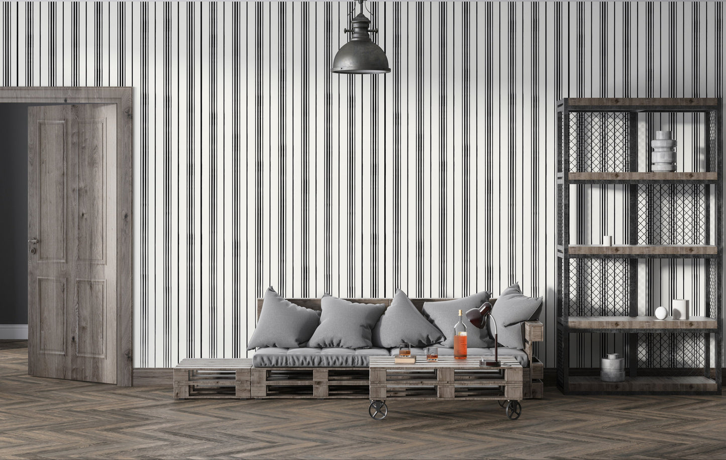 A modern interior scene with a gray cushioned sofa set against a white wall patterned with thin vertical black stripes. A wooden side table and black desk lamp sit beside bottles and glasses on a coffee table, while an industrial-style shelving unit with metal mesh panels stands on the right.
