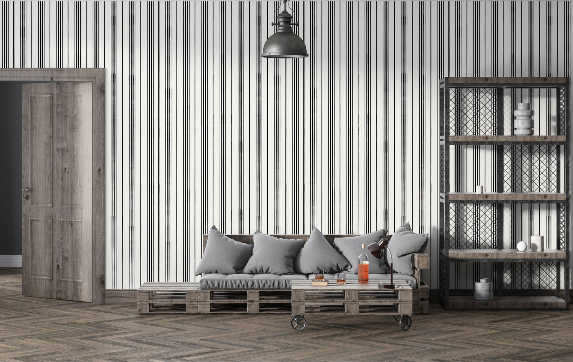 A modern interior scene with a gray cushioned sofa set against a white wall patterned with thin vertical black stripes. A wooden side table and black desk lamp sit beside bottles and glasses on a coffee table, while an industrial-style shelving unit with metal mesh panels stands on the right.