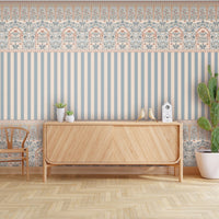 Rajmahal Floral Stripe Wallpaper and Blue Palace Wall  shown on a living room wall behind a wooden cabinet, chair, and cactus plant, as seen.