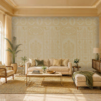 Bright, elegant living room with warm natural light streaming through an arched window. A cream sofa sits against a decorative beige-and-white patterned feature wall, flanked by potted plants and small side tables. Natural textures, including a woven rattan armchair, jute area rug, and wooden sideboard, create a relaxed, upscale aesthetic. Green accent pillows, ceramics, and fresh flowers add subtle color, while a marble floor and coffered ceiling enhance the room’s refined, airy feel.