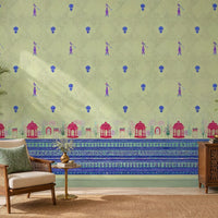Royal Garden Heritage Wallpaper in Pistachio Green featuring intricate floral motifs, elegant peacock-inspired details, and decorative Mughal garden architecture borders in royal blue and rani pink, styled in a bright living room with cane furniture, carved wooden cabinetry, indoor plants, and natural woven textures.